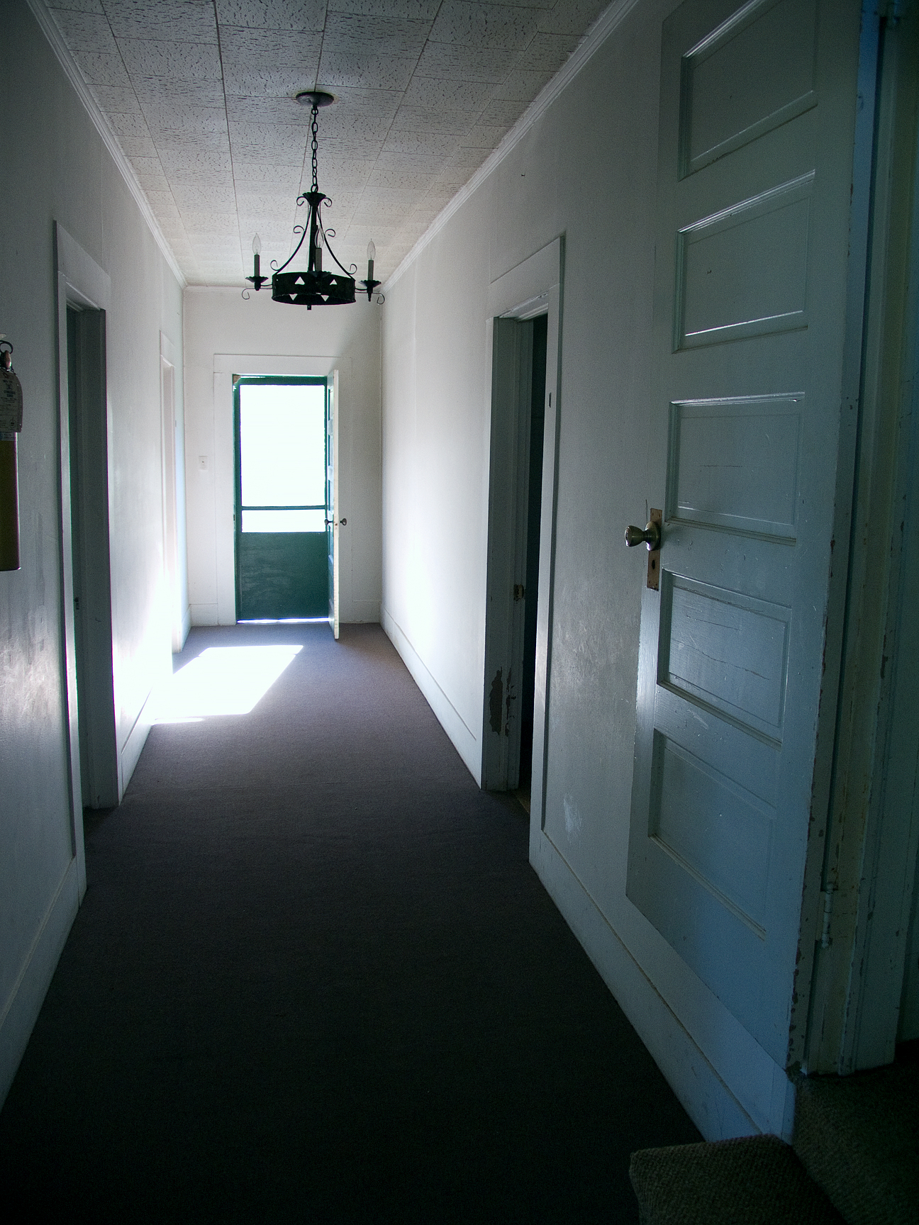 (above) This hallway leads from the living area. To the immediate right, you will see a step leading up to a five panel door which leads to the stair to the second floor. Now why would there be a need to close off the second floor? The ceiling's acoustical tile can't be original.