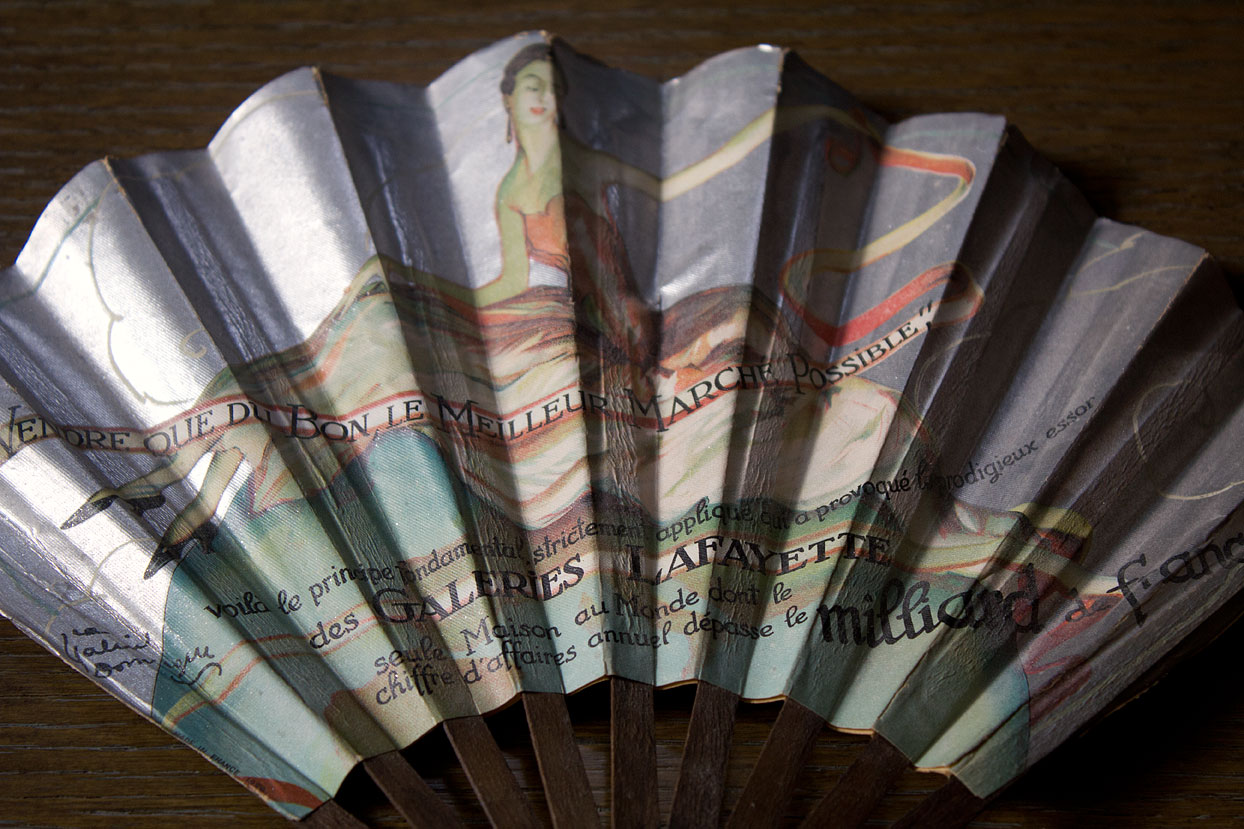 (above) The back side of the above fan is signed by a different artist and appears to be an ad for Galleries Lafayette. In tiny letters on the right edge are the words “Made in France 1926."